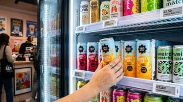 Gen Z shopper reaching for canned bubble tea on a retail shelf, showcasing low‑sugar, vegan RTD bubble tea for grab‑and‑go sales.